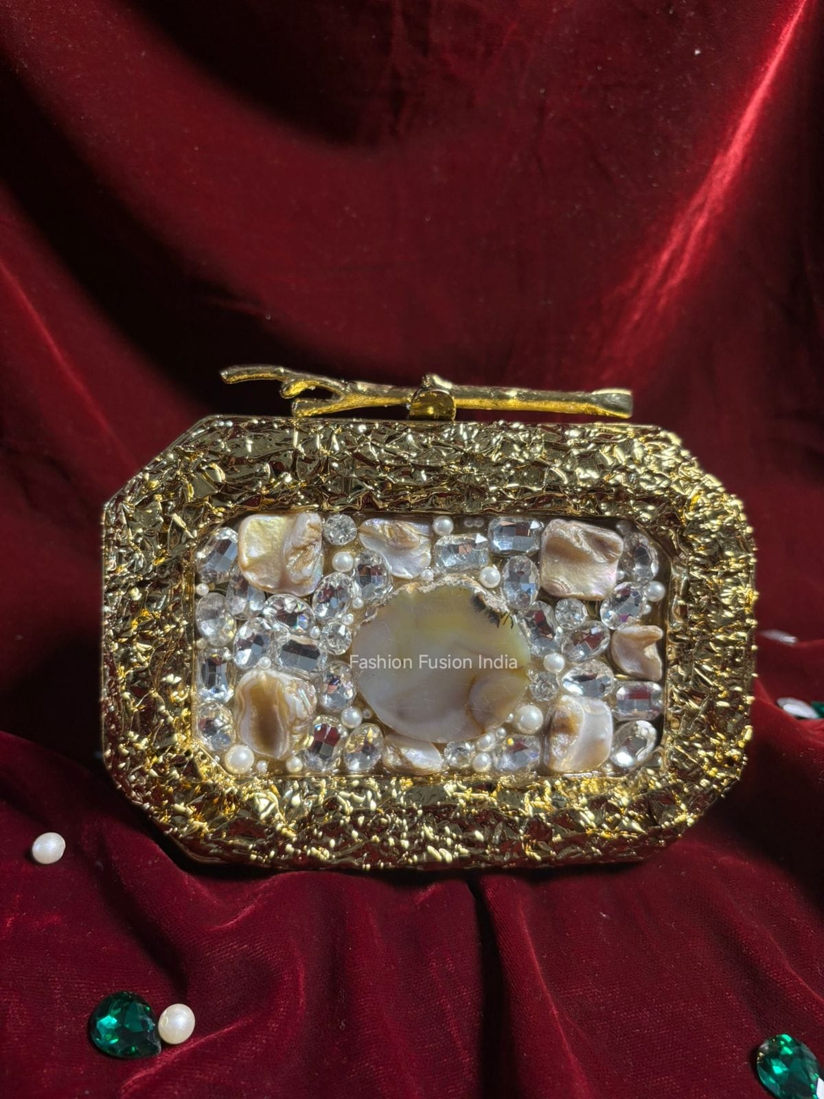 Decorative belt buckle with gold and stone design on a red fabric background