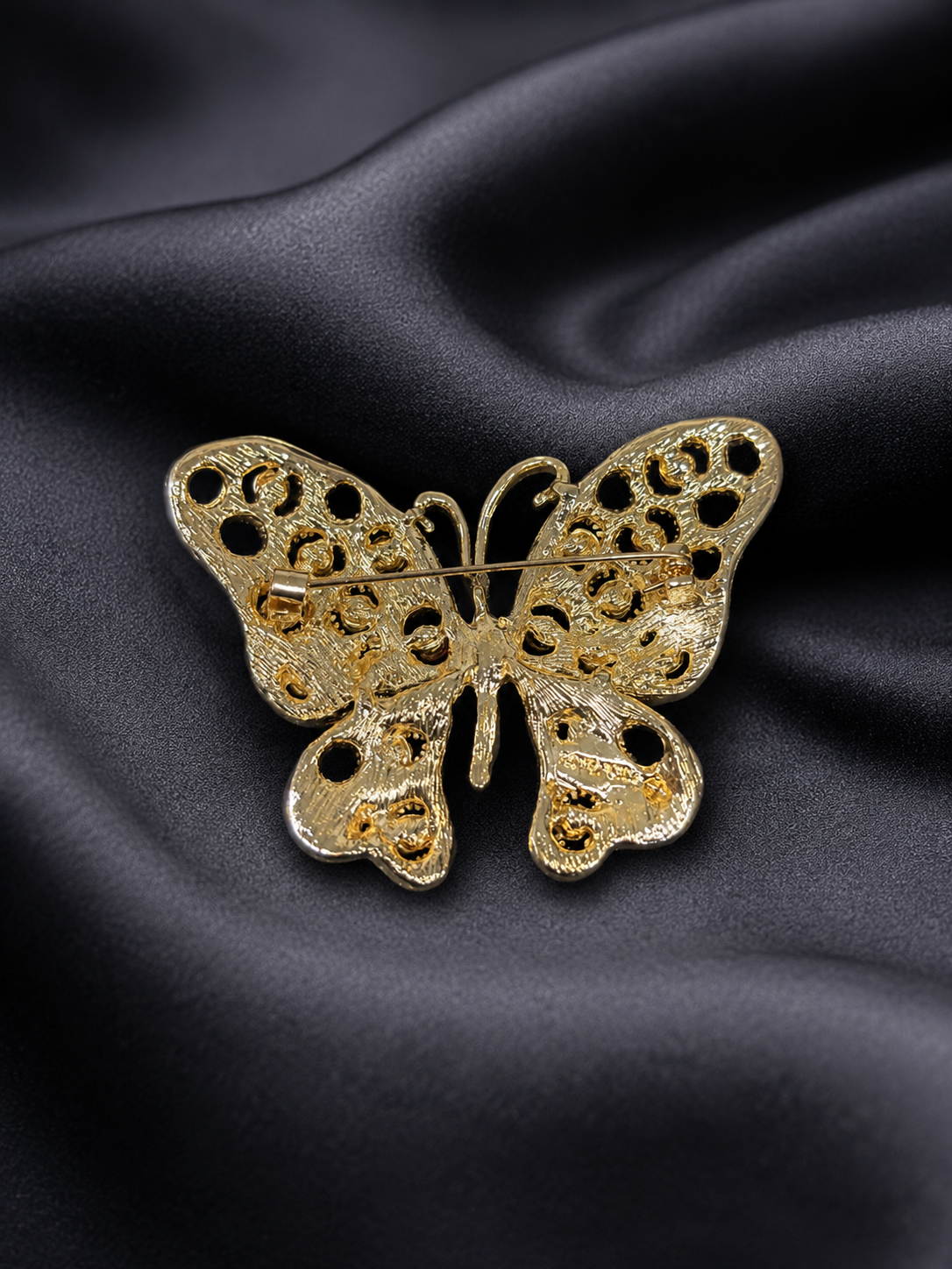 Gold butterfly brooch on black satin fabric