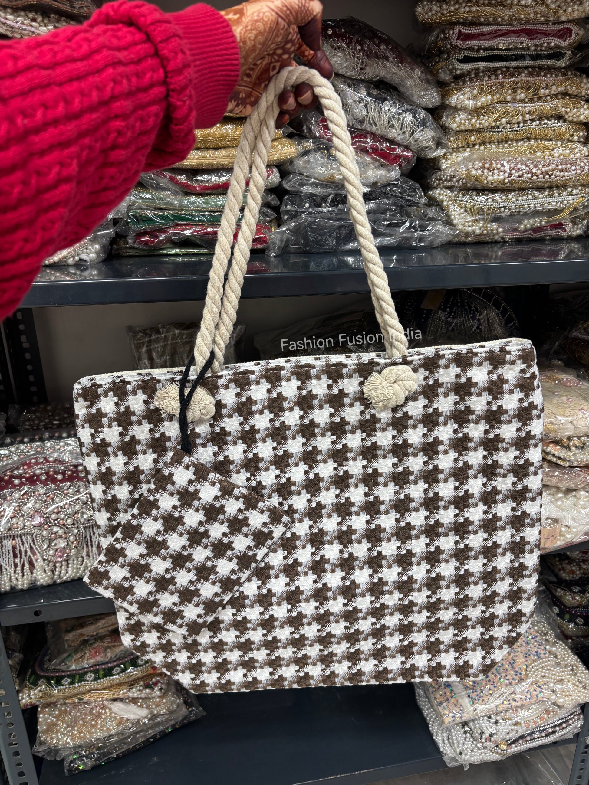 Houndstooth patterned bag with rope handle held by a person in a red sweater.