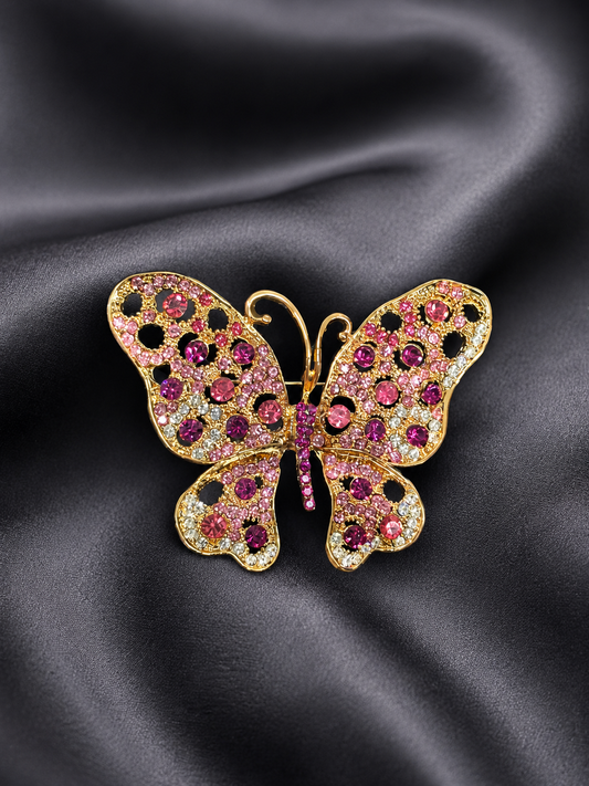 Gold butterfly brooch with gemstones on a black satin background