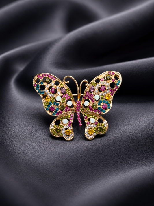 Butterfly-shaped jewelry with colorful gemstones on a dark fabric background