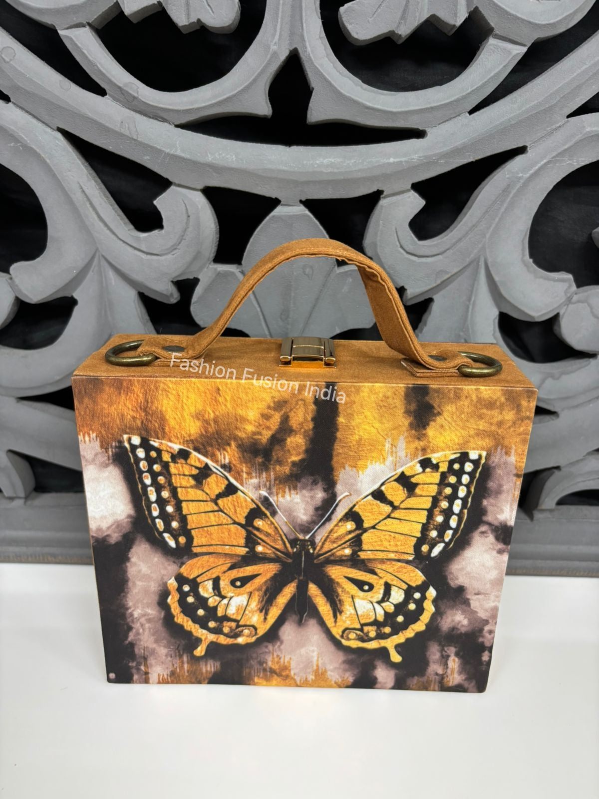 Artistic butterfly design wooden clutch bag against carved grey backdrop.