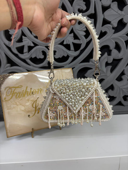 Decorative handbag with beaded details held by a hand, against a decorative wall.