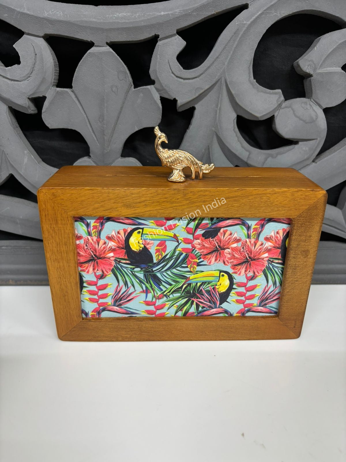 Wooden tropical print box with toucan artwork and a gold peacock handle, styled on a wooden table with home décor accents.