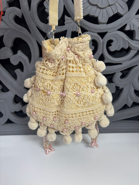 Decorative handbag with pom-poms and pink embellishments against a decorative gray background