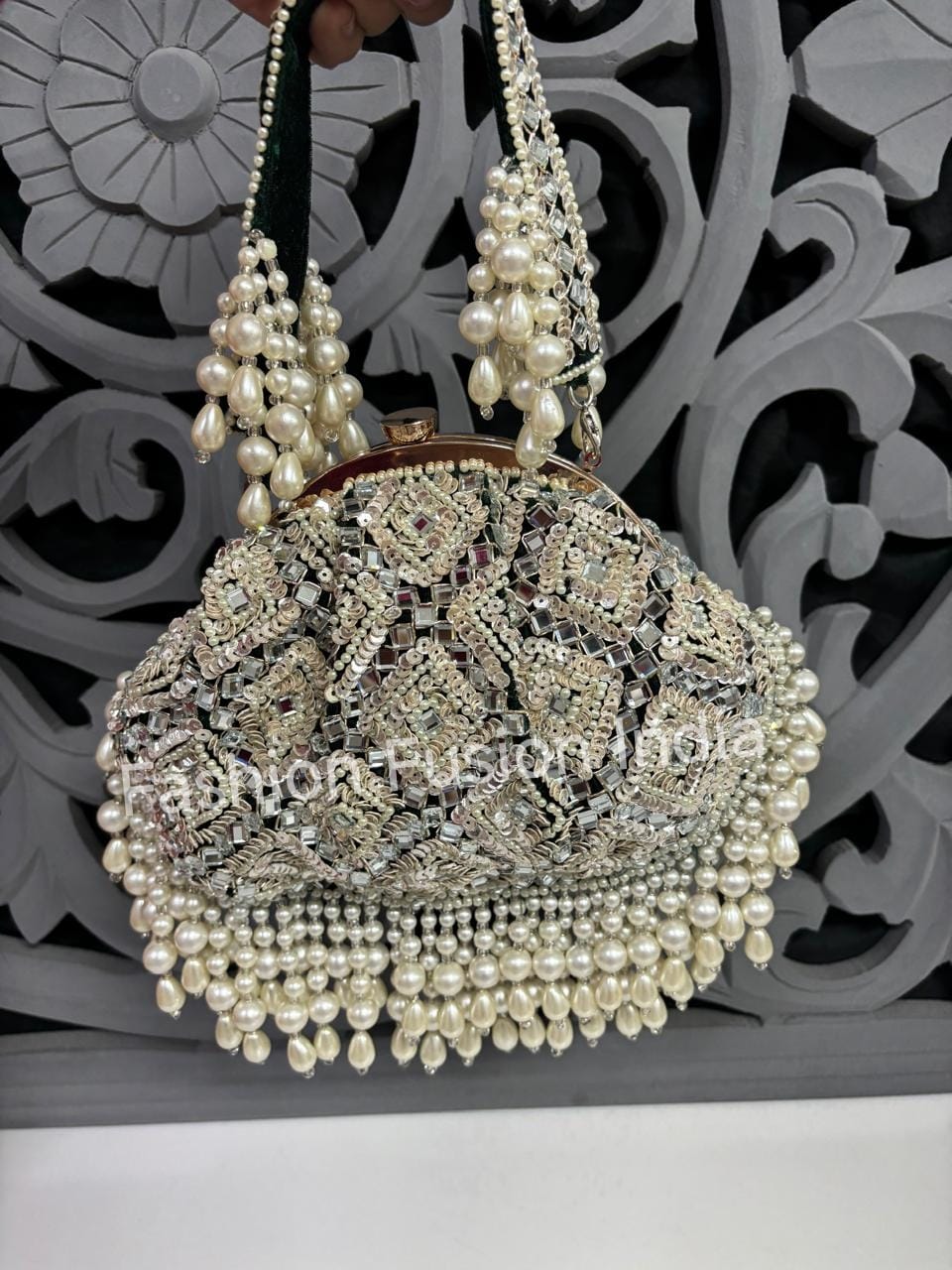 Decorative handbag with pearls and intricate design against a decorative background