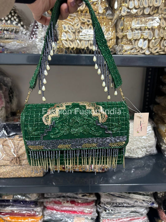 Green beaded handbag with intricate designs held by a hand against a blurred background.