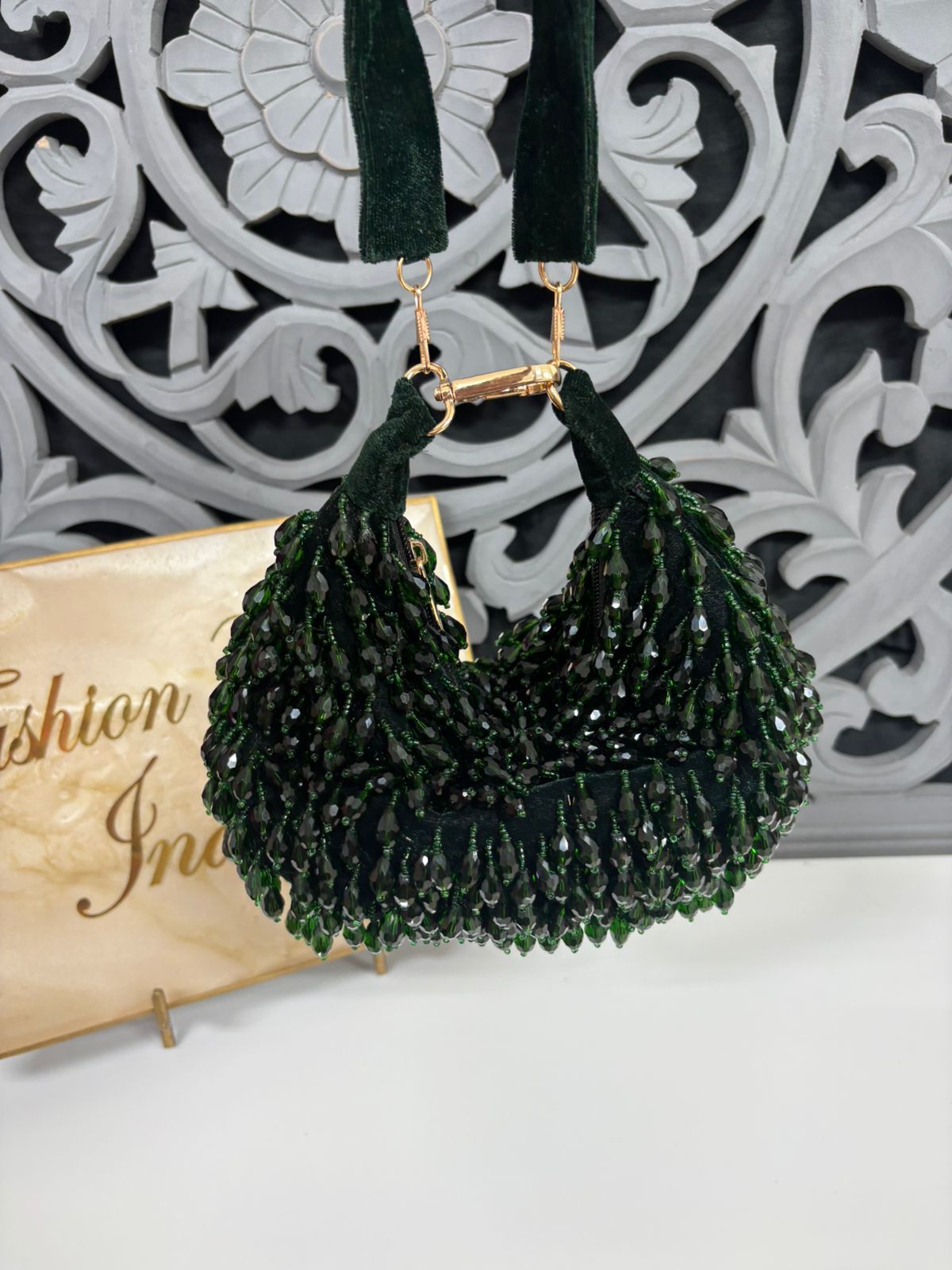 Green beaded handbag with gold accents on a decorative background
