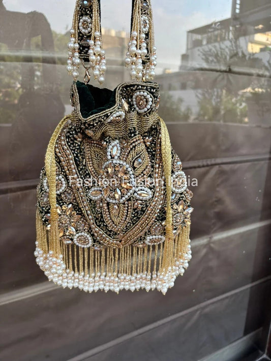 Decorative handbag with intricate beadwork and pearl details on a reflective surface.