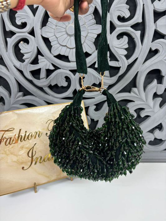 Green beaded handbag held by a hand against a decorative white and gray background.