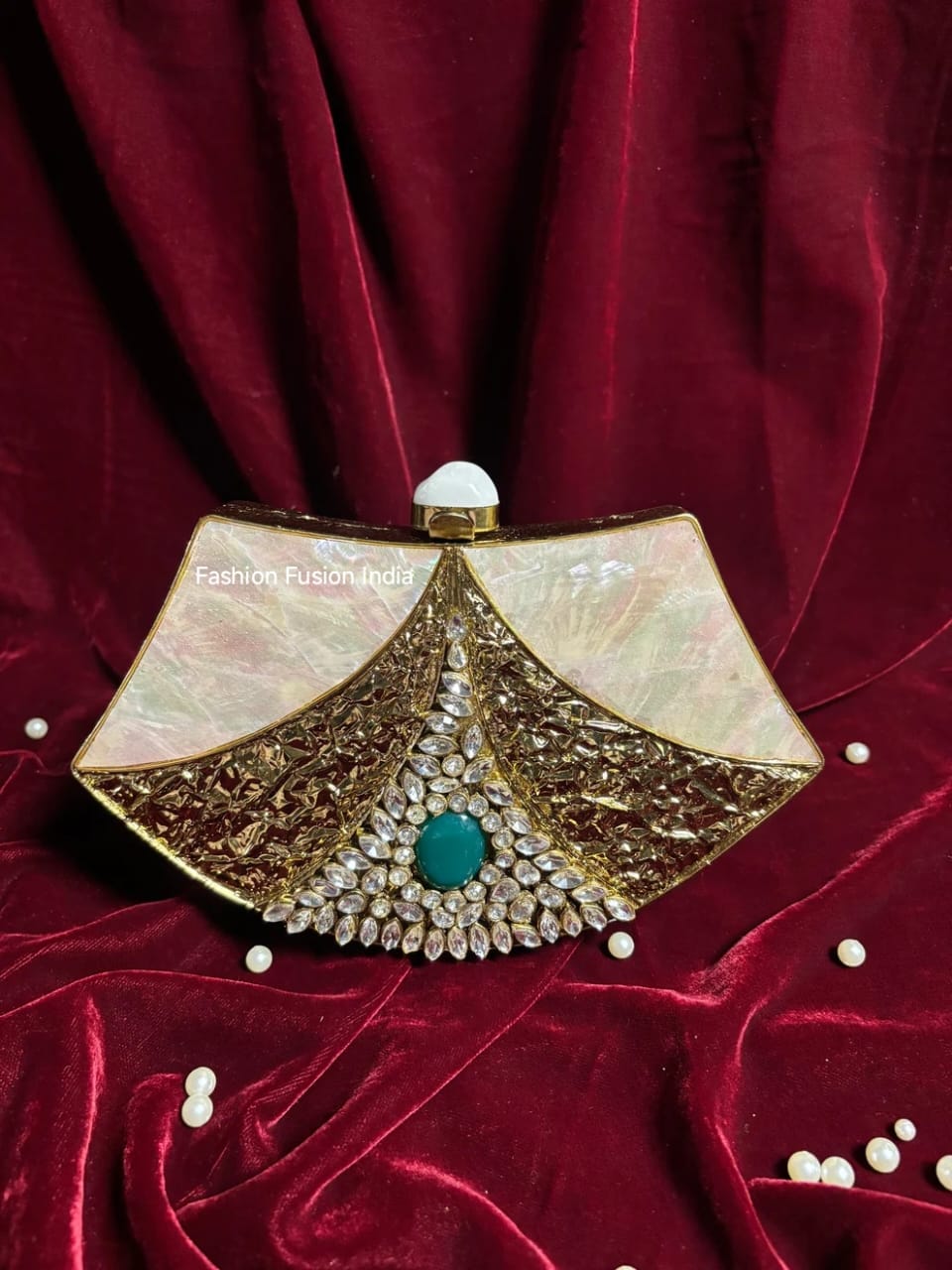 Decorative clutch bag with gold and pearl details on a red fabric background