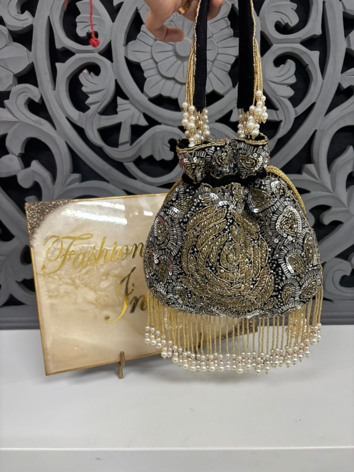 Decorative handbag with beads and pearls on a stand with 'Fashion' card in the background