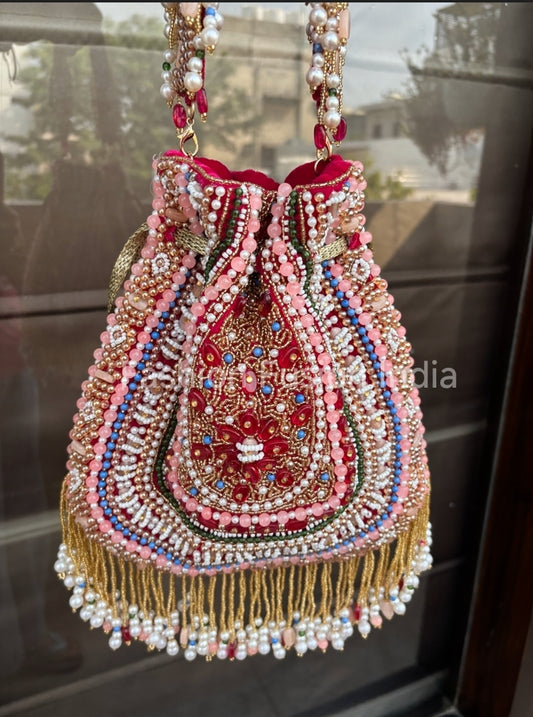 Decorative handbag with intricate beadwork and embroidery on a reflective surface.