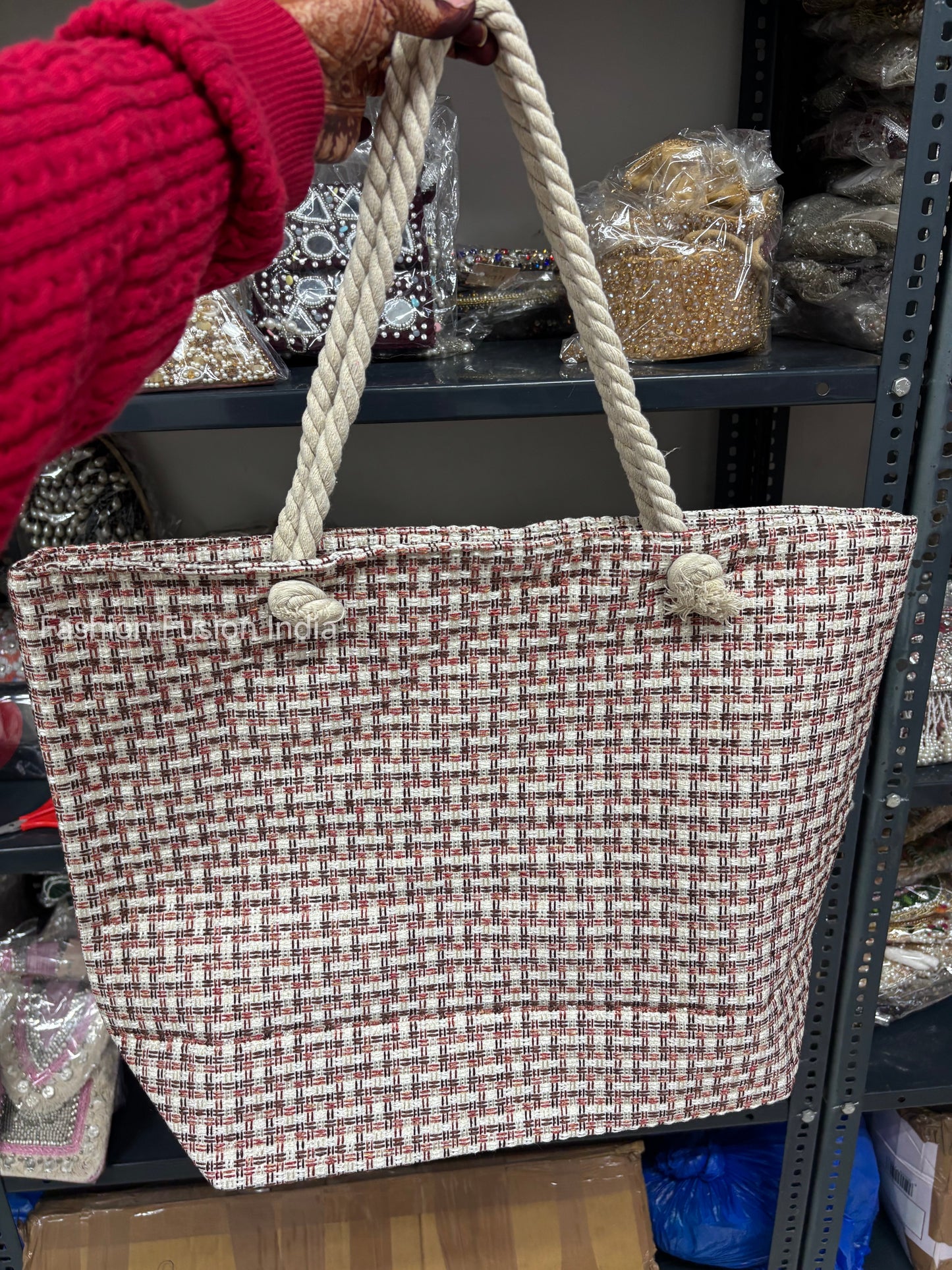 Person holding a woven tote bag in a store setting with shelves and products in the background.
