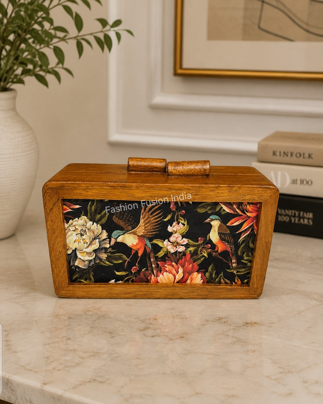 Wooden box clutch with floral and bird artwork on elegant indoor background.