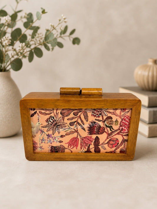 Wooden box clutch with vintage floral and bird print against carved grey backdrop.