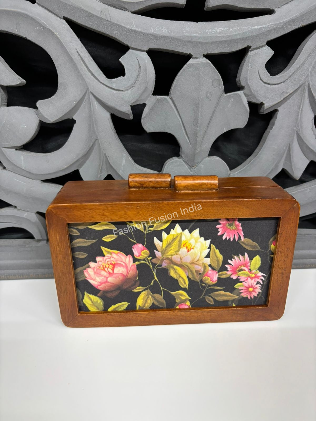Vintage floral wooden clutch bag on warm indoor décor background.