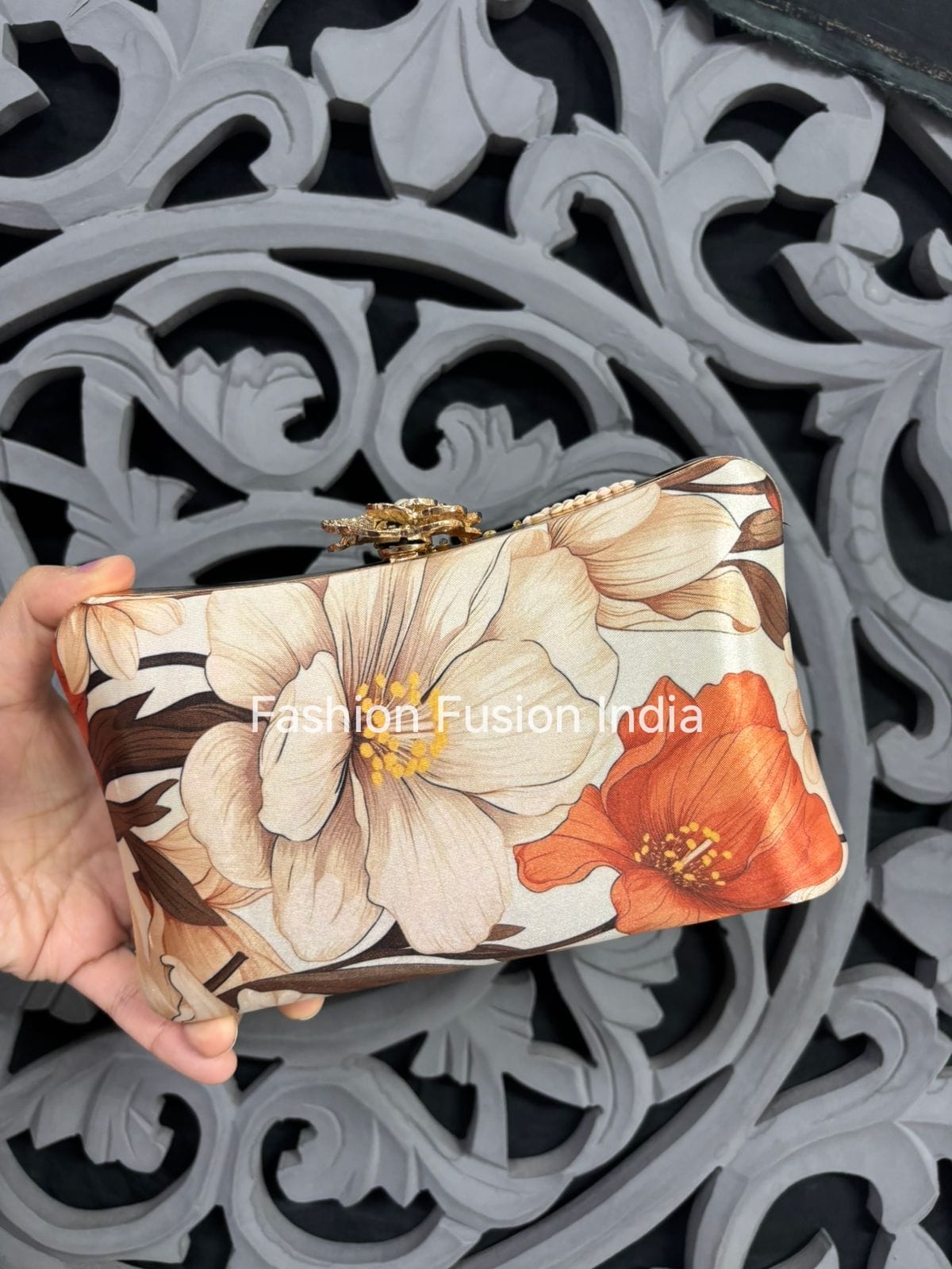 Floral clutch bag held by a hand with decorative background
