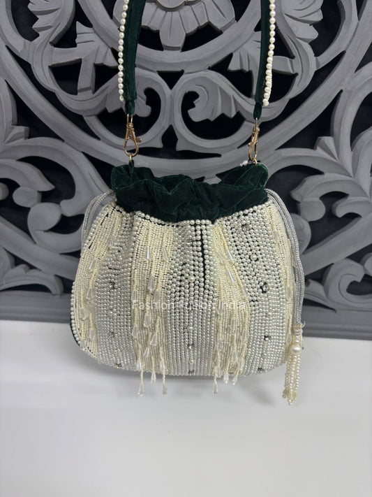 Decorative handbag with beads and fringes on a white surface with a decorative black and white background.