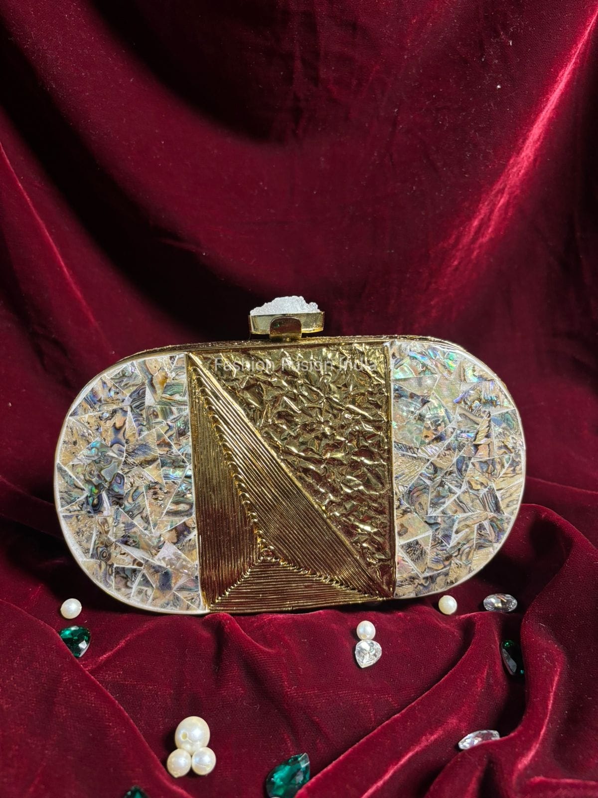 Decorative gold clutch on a red velvet surface with scattered pearls and gemstones.