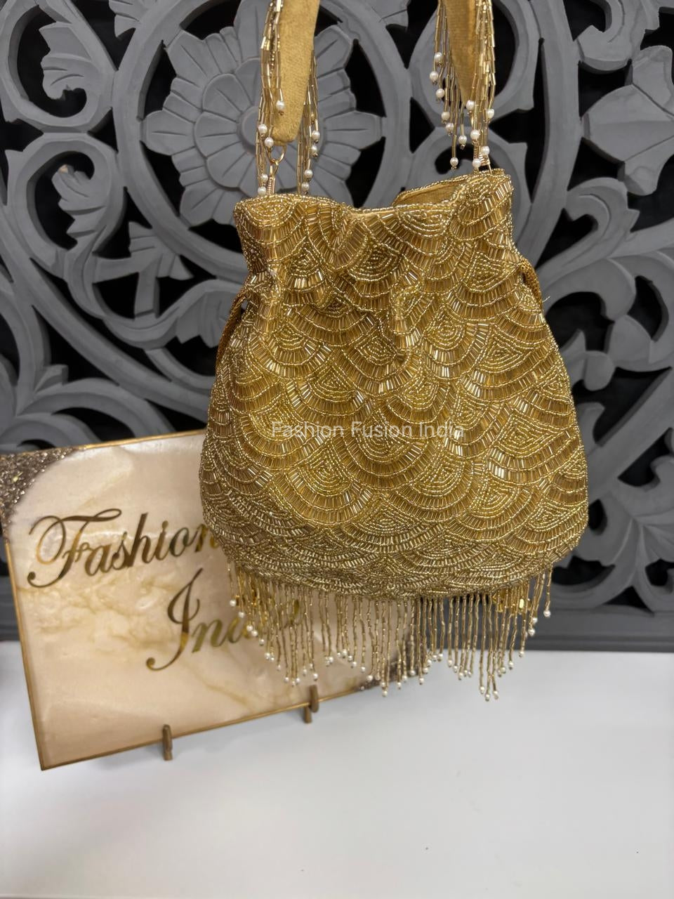 Gold beaded handbag with fringe on a decorative background