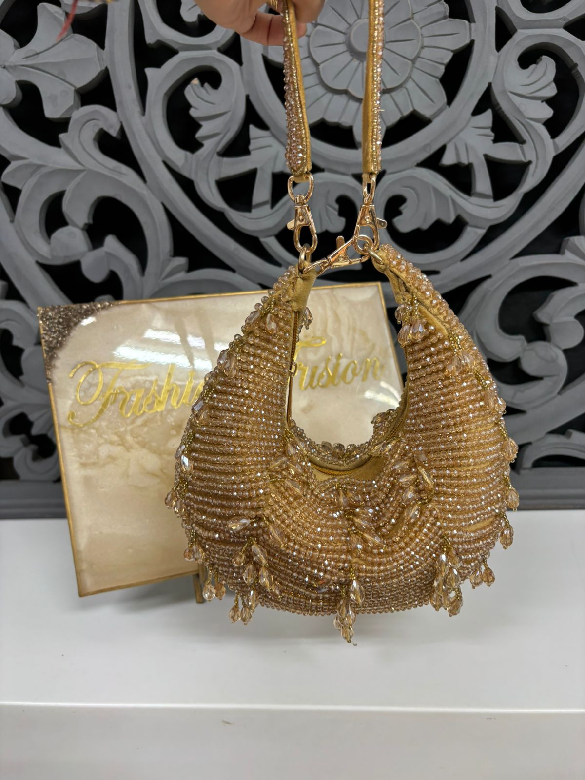 Gold beaded handbag with intricate design on a decorative background