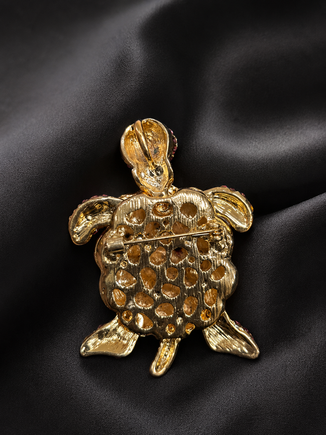 Gold turtle-shaped jewelry box on a black satin background
