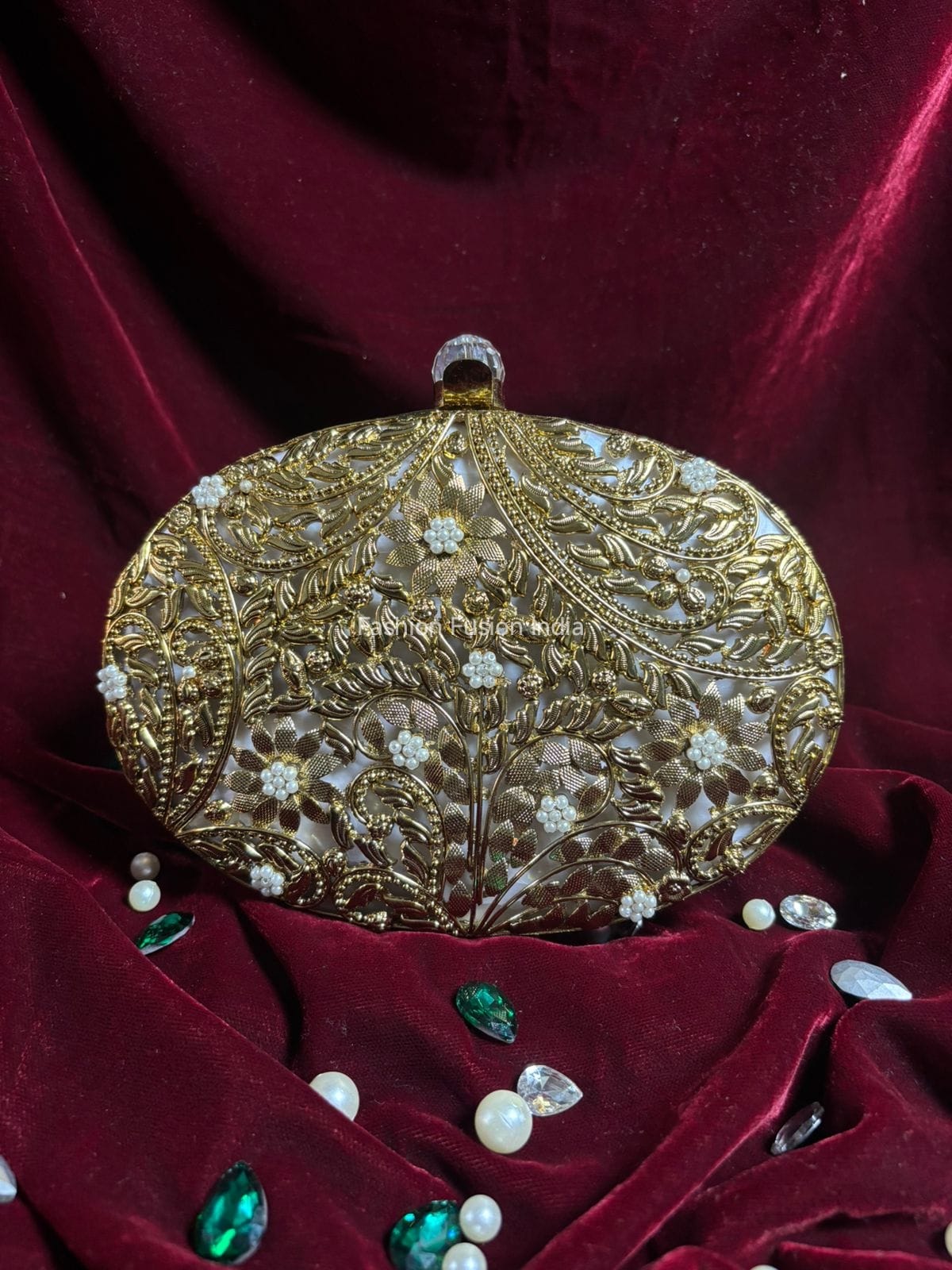 Decorative gold clutch with gemstones on a red velvet background