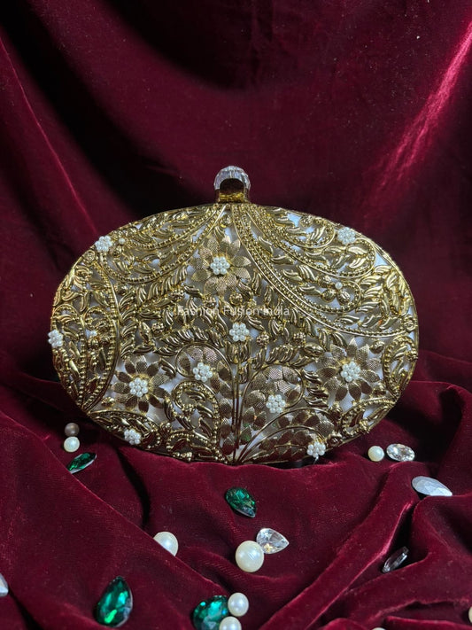 Decorative gold clutch with gemstones on a red velvet background