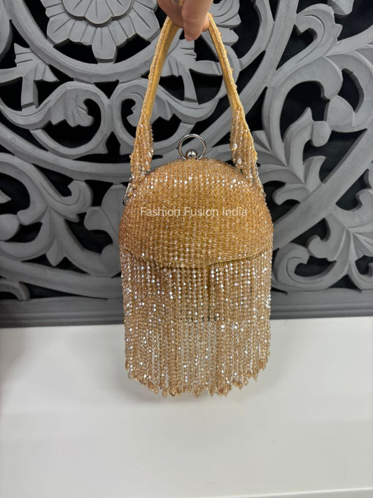 Gold beaded handbag held by a hand against an ornate white and gray decorative wall.
