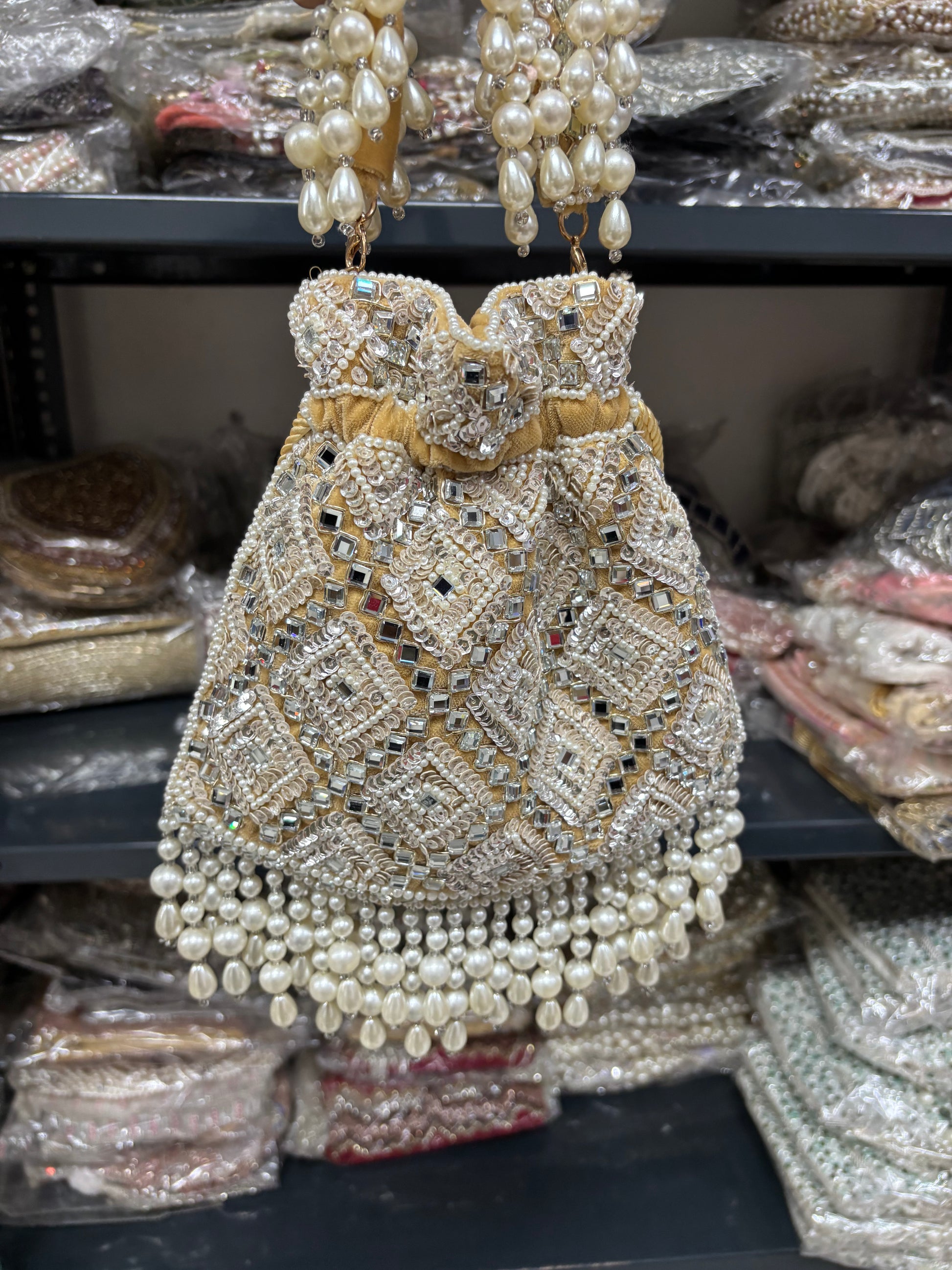 Decorative handbag with pearls and beads on a shelf with similar items.