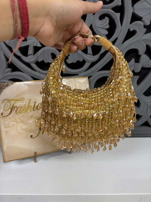 Gold beaded handbag held by a hand with a decorative background