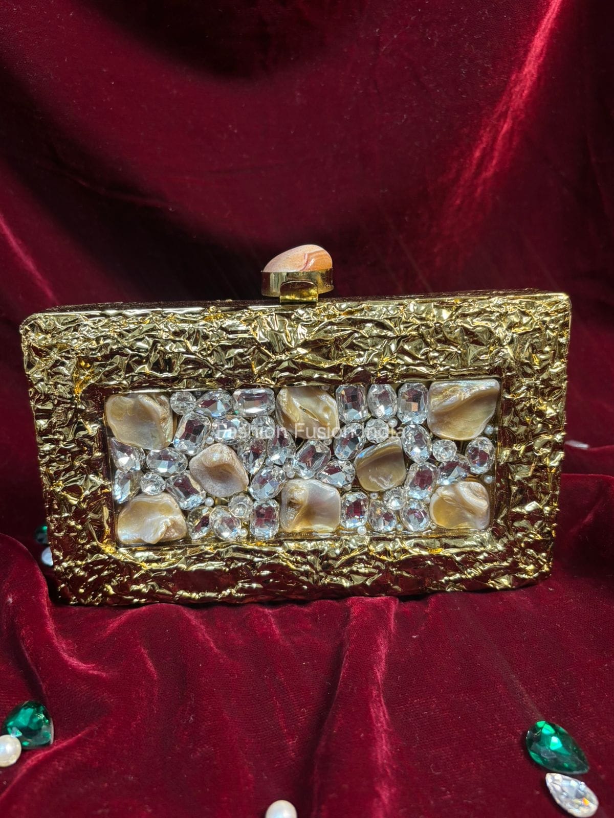 Gold clutch with decorative stones on a red background