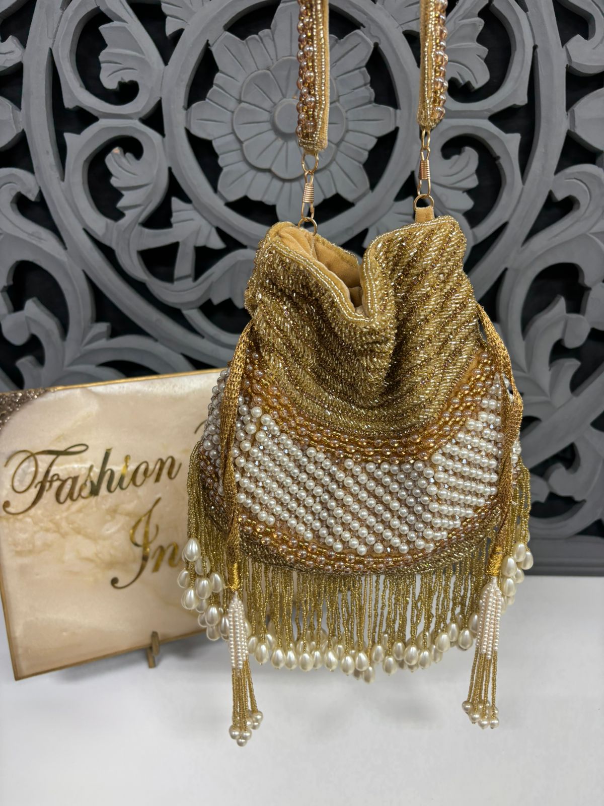 Gold beaded handbag with tassels on a decorative background