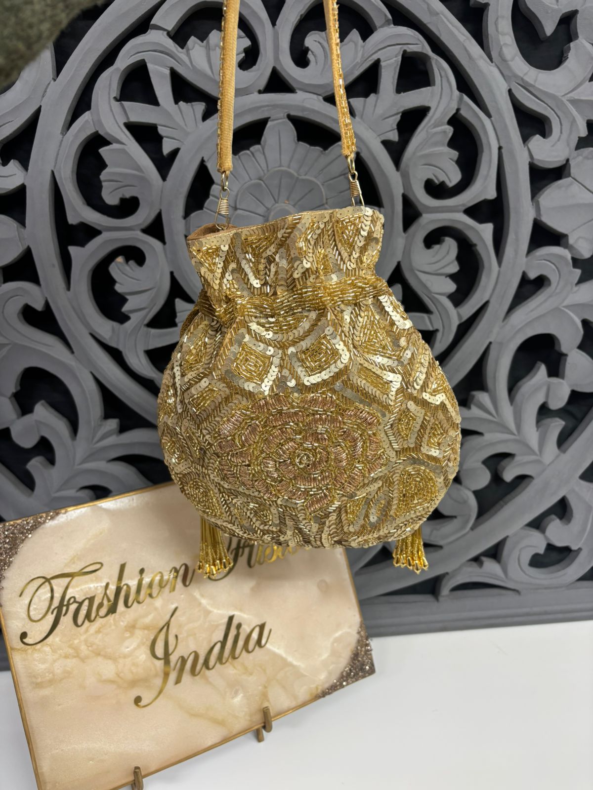 Gold beaded handbag on a decorative stand with 'Fashion from India' card