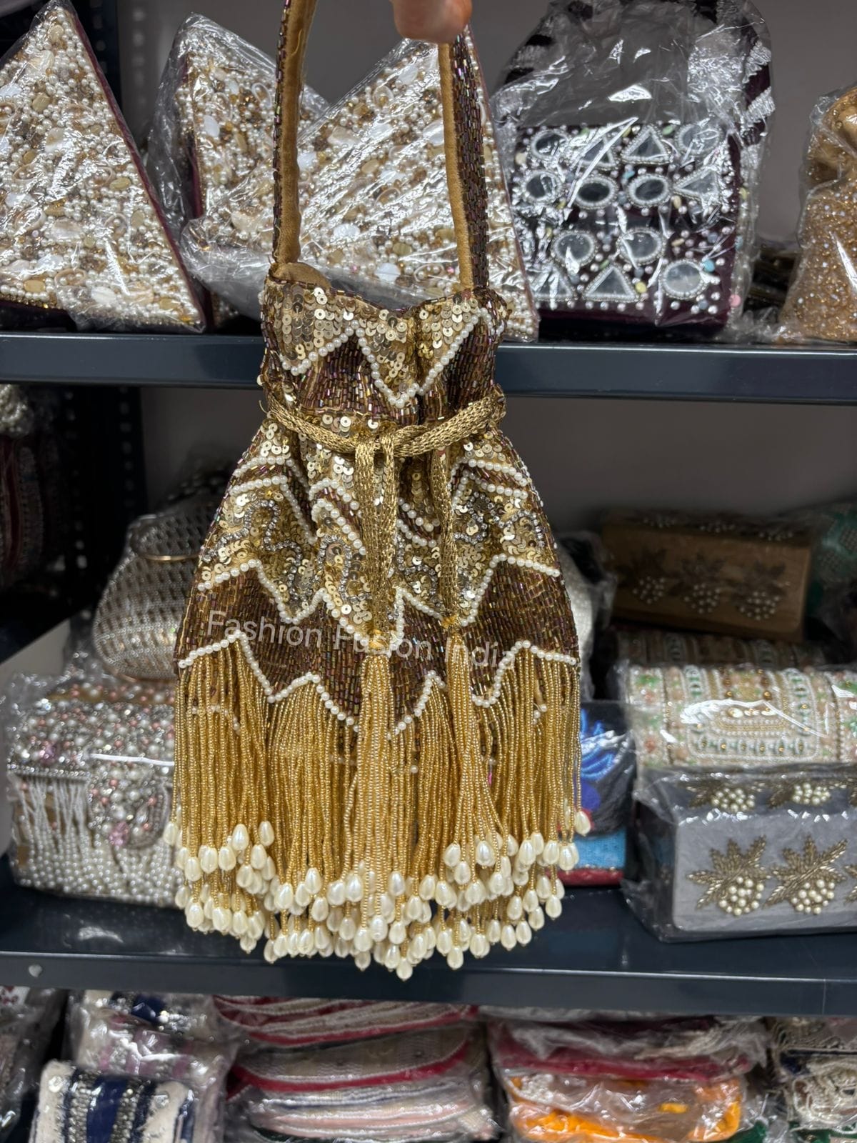 Gold beaded handbag with tassels on a shelf with other decorative items.