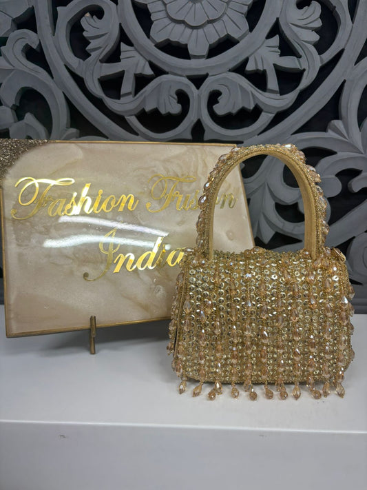 Gold beaded handbag with 'Fashion First India' sign in the background