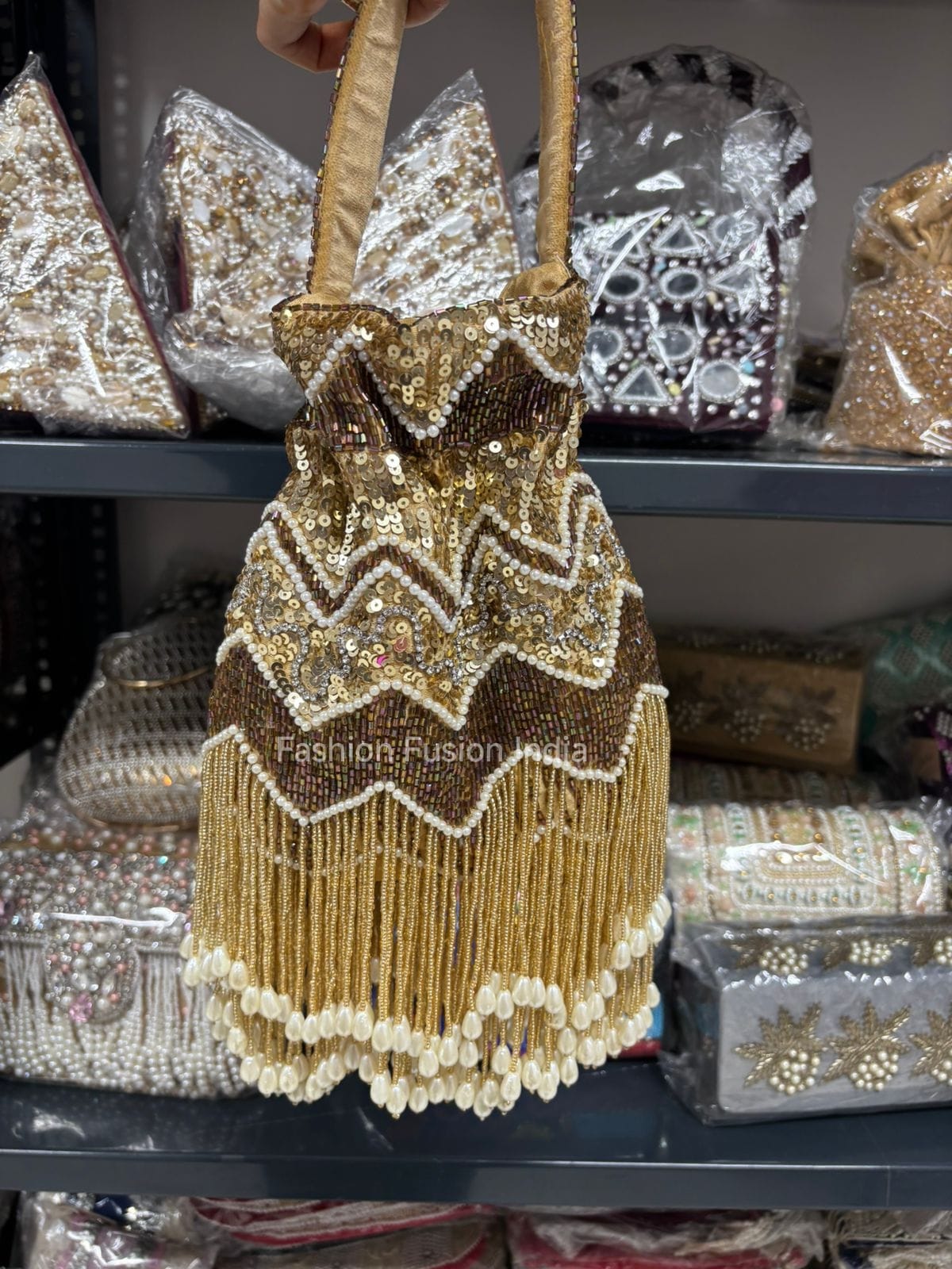 Gold beaded handbag with decorative patterns on a shelf with similar items.