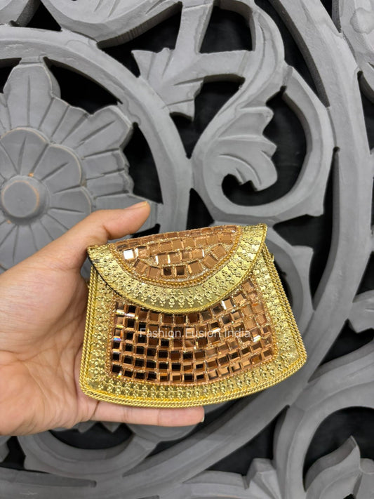 Gold and brown patterned pouch held by a hand against an ornate gray background