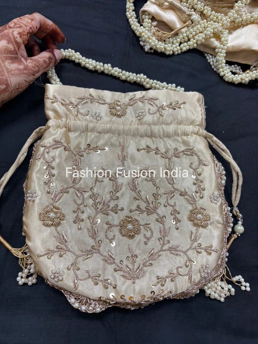 Decorative handbag with floral embroidery and pearl details on a dark background, branded 'Fashion Fusion India'.