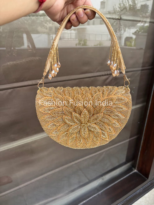 Gold handbag with intricate design held by a hand, blurred background