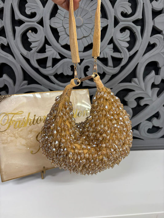 Gold beaded handbag held by a hand with a decorative background