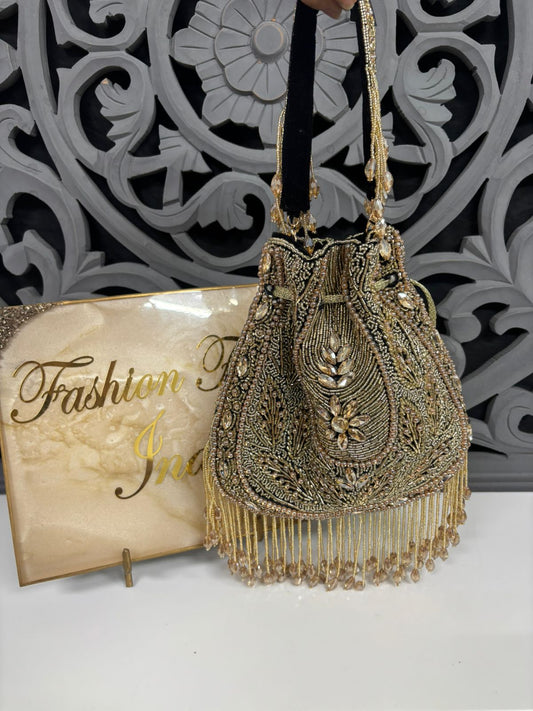Decorative handbag with intricate designs and beads on a white surface with a decorative wall in the background.