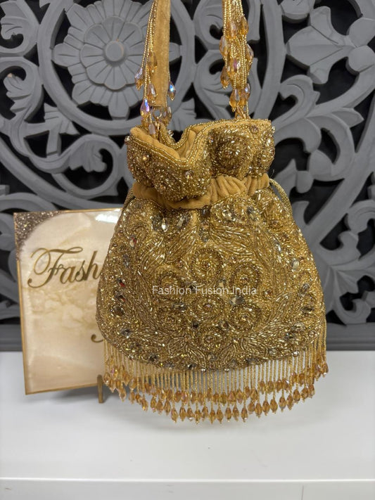 Gold embroidered handbag with decorative elements on a white surface with a decorative gray background.