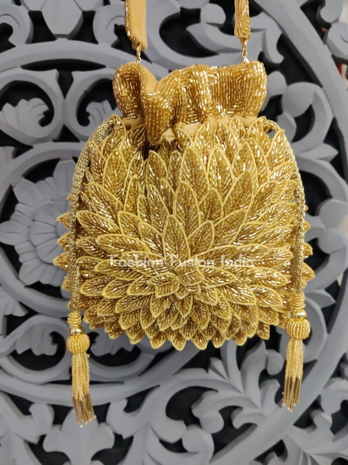 Gold embroidered handbag with tassels on a decorative white and black background
