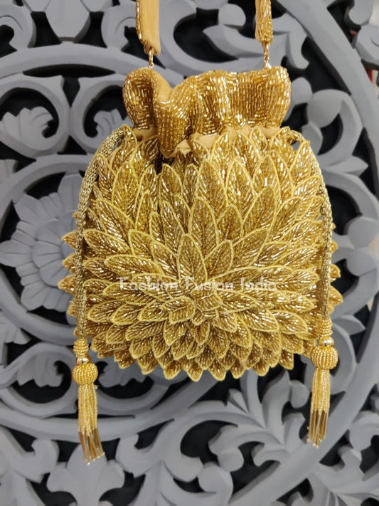 Gold embroidered handbag with tassels on a decorative white and black background