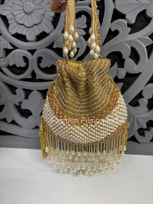 Gold beaded handbag with pearl details against a decorative white and black background