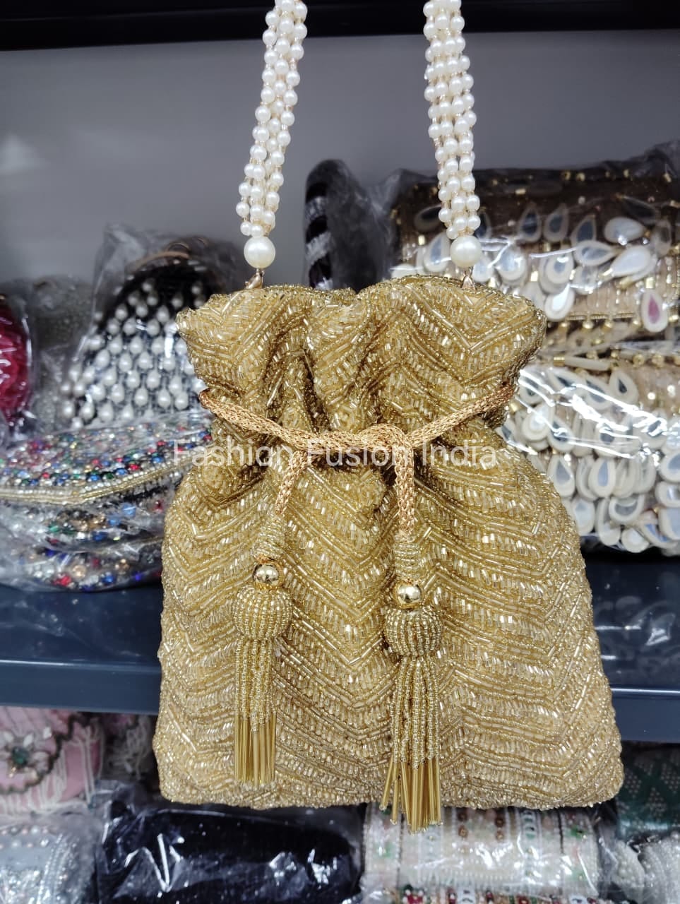 Gold beaded handbag with pearl handles on a blurred background