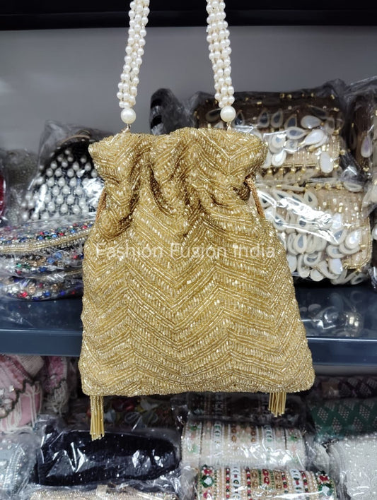 Gold beaded handbag with pearl handle on a blurred background