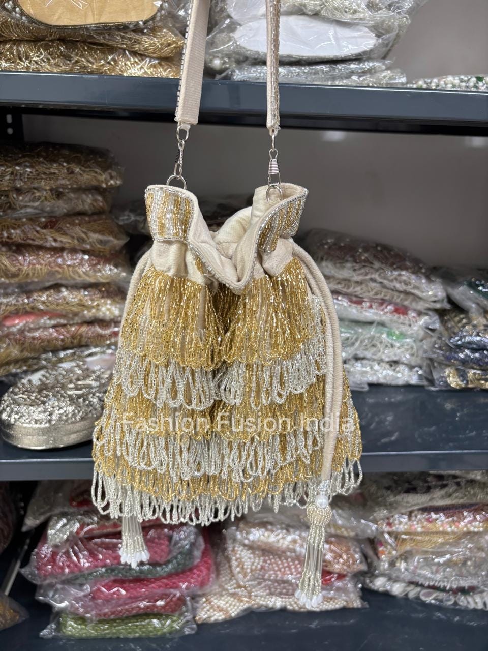 Gold beaded handbag with a drawstring top on a shelf with plastic-wrapped items.